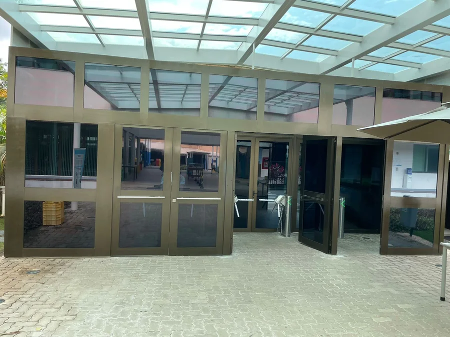 Entrada com porta e painéis de vidro, estrutura metálica e cobertura envidraçada; projeto real do grupo.
