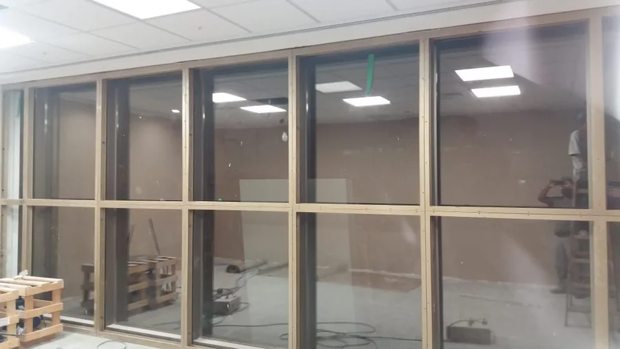 Fechamento de vidro em perfis claros em ambiente comercial com iluminação de teto; projeto real do grupo.