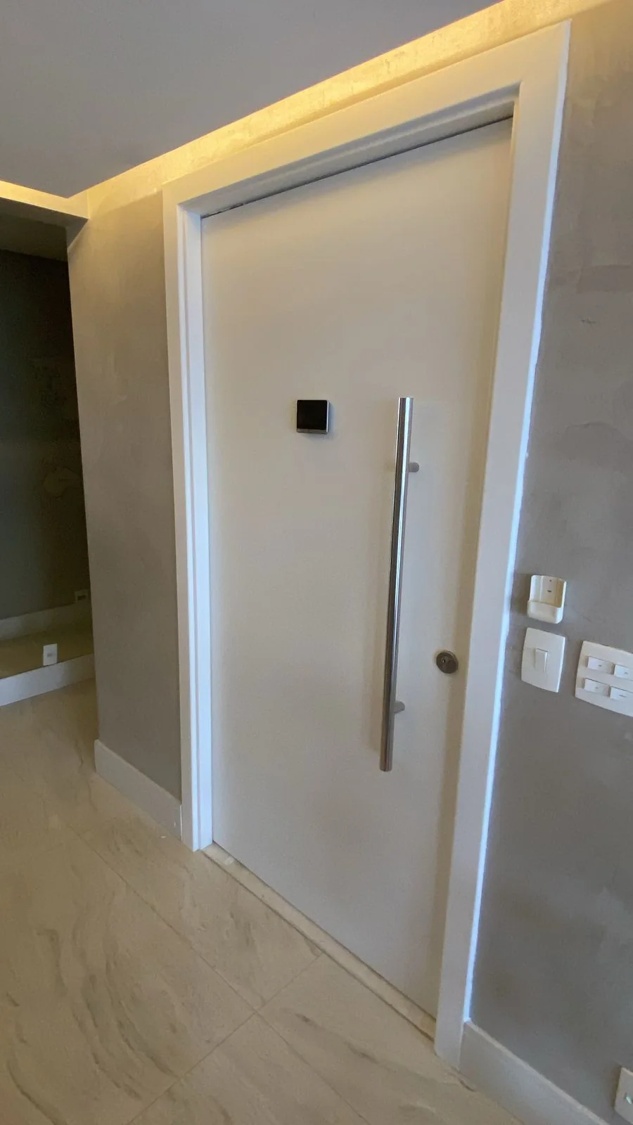 Porta blindada Top Blind: porta branca instalada em entrada residencial com iluminação no teto.